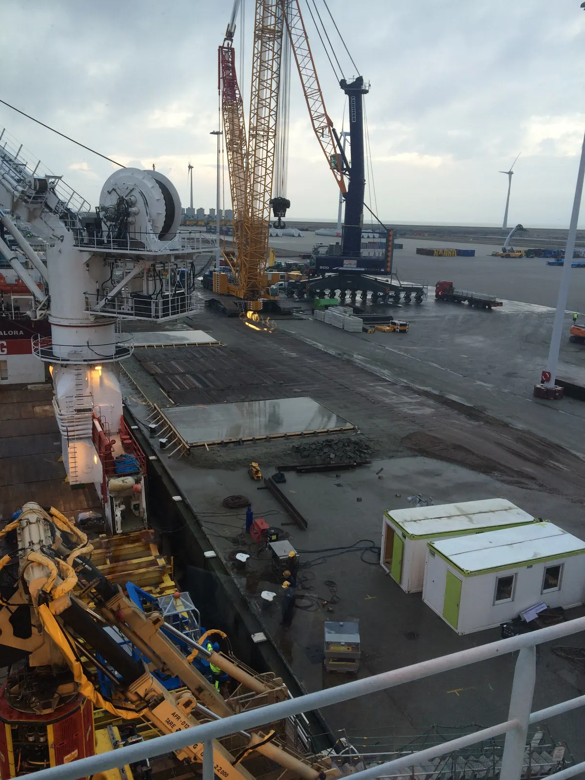 Trianel Windpark Borkum — offshore cable-lay vessel at port with wind turbine array and cranage in background