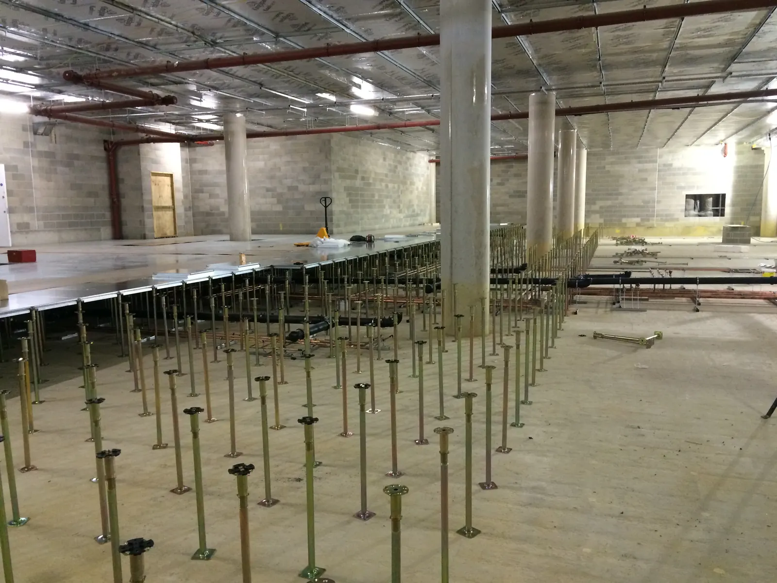 AELTC Wimbledon — basement floor void showing jack pedestals for raised access floor system