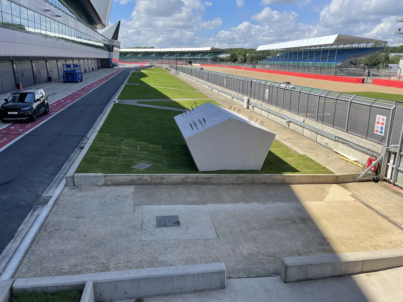 Craig Garbutt inspecting the bespoke shaped concrete sky bridge foundation in the Silverstone Racing Circuit pit lane — complex structural package delivered within a live Formula 1 and motorsport venue