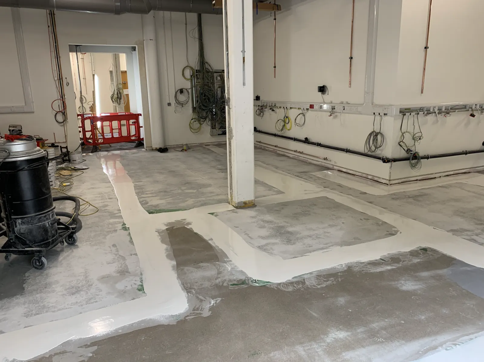Advanced Materials Testing Facility — resin floor coating being applied around structural column, services first-fix