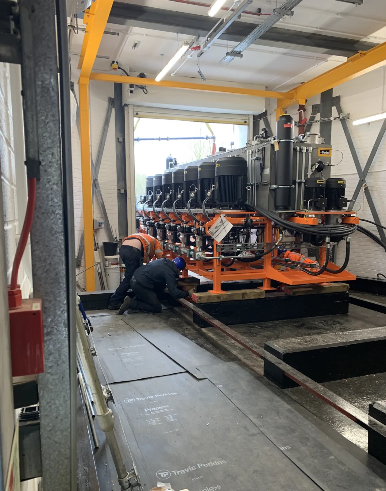 Bank of hydraulic power units being positioned and connected, engineers working at the base of the skid